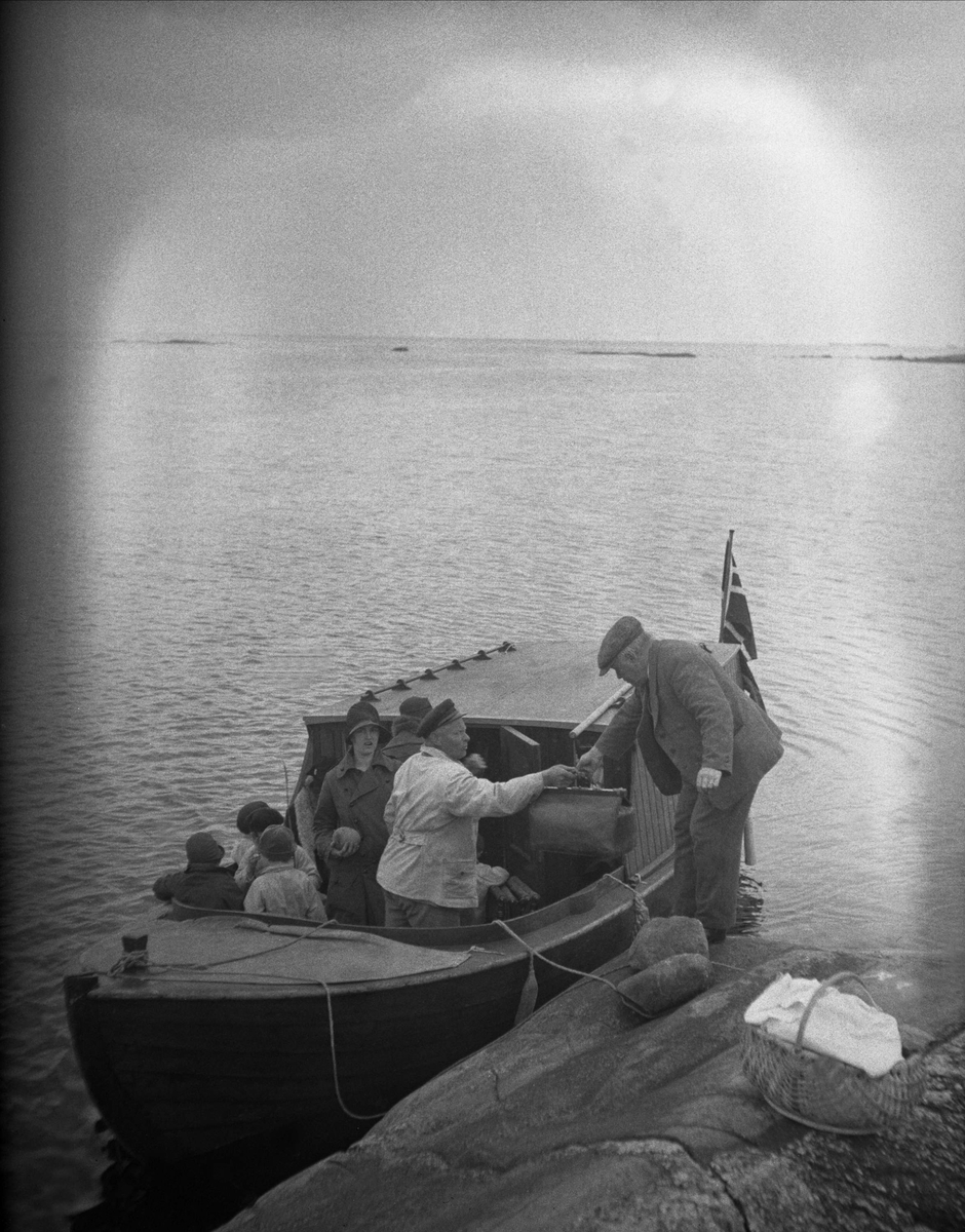 En mann går ombord i en motorbåt fra et svaberg, Storesand, Hvaler. Fotografert 19. mai 1929.