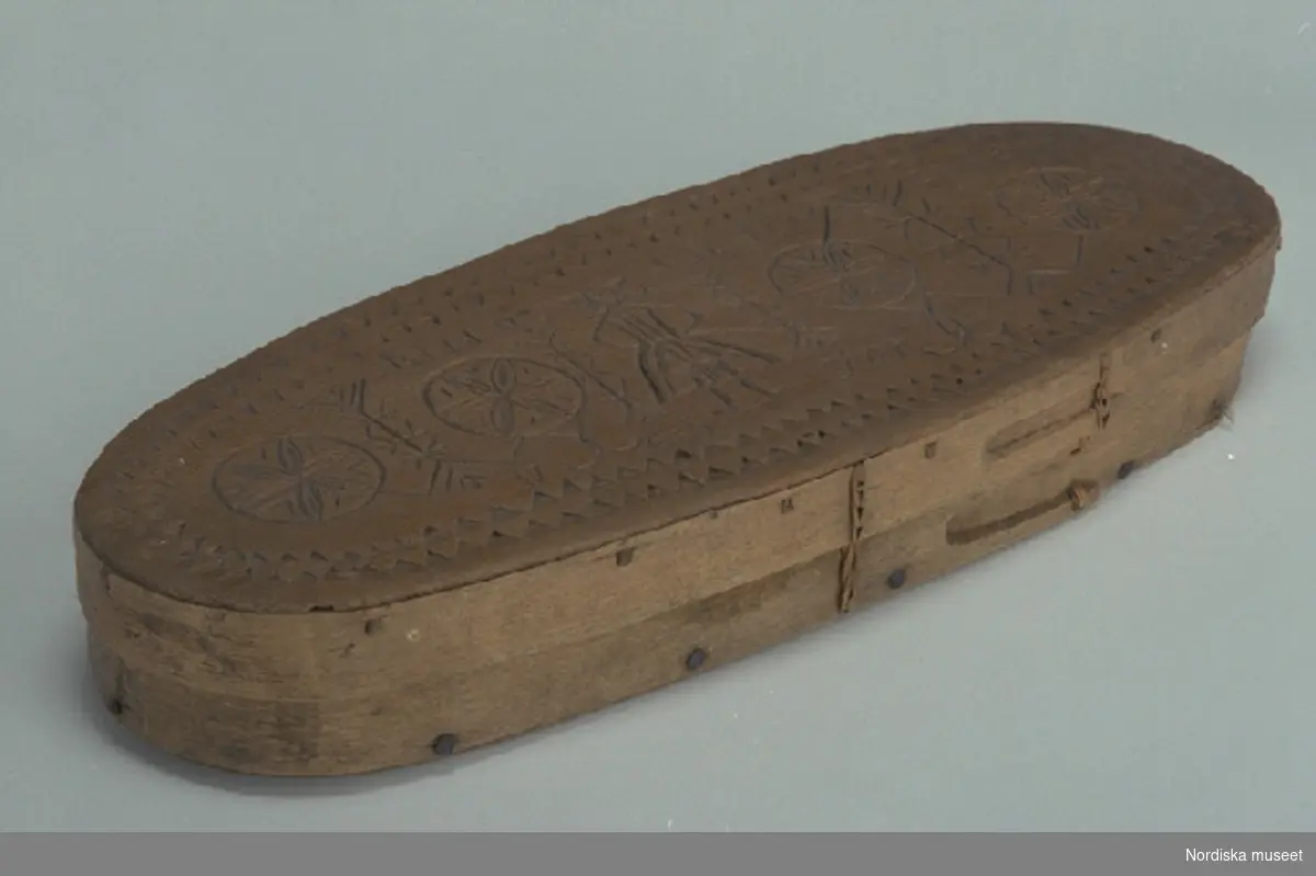 Inventering Sesam 1997-1998:
L 40, B 15, H 6 cm
Ljusask, oval, Botten och lock av barrträ med svep av lövträ, med falsar. Bottensvepet fästat med järnnubbar,  lockets svep fästat med dymlingar av trä. Hopfästning av svepen med rottågor, kedjesöm, två rader. Skuren ornamentik på locket, karvsnitt och uddsnitt, föreställande  människa. På locket inskuret "ANNO D 16 NOVEMBER 1743  JOS".
Begagnad vid upphämtandet av julljusen för kyrkans behov inom den rote som Näs by tillhört.
AMB

