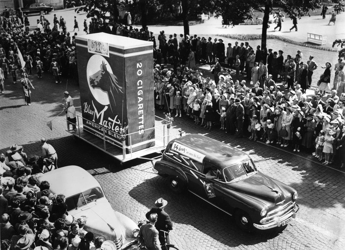 "Oslo-dagen" 14. juni 1952. Reklame for Blue Master sigaretter i et opptog med mennesker som har samlet seg rundt.