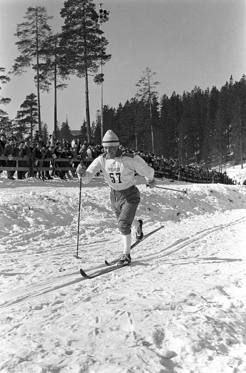 Skiløper med startnummer 57 i Holmenkollen. Publikum langs løypa.   Holmenkollrennene 1963.