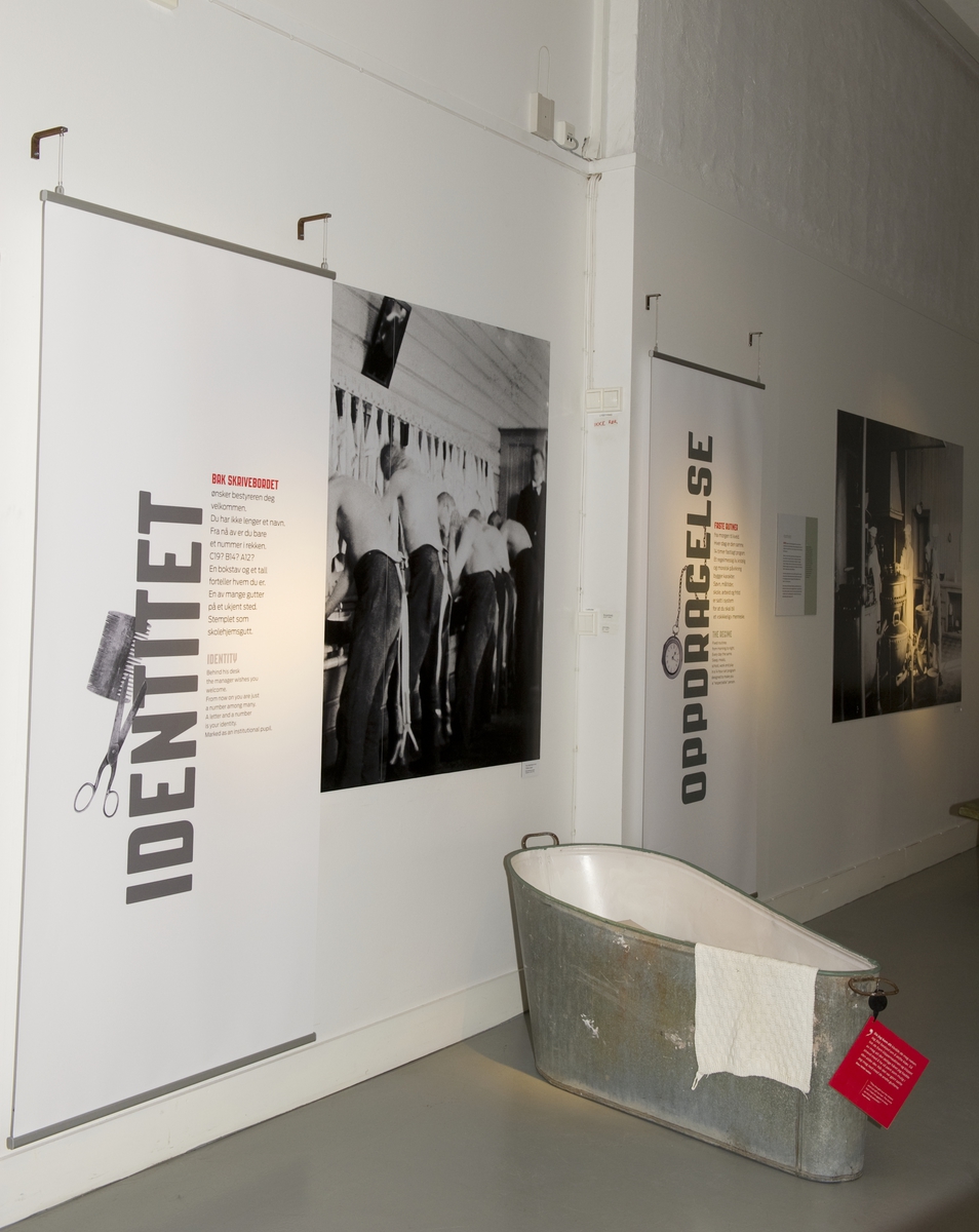 Utstillingsplakat og rekvisitter. På badekaret henger det en rød lapp med et sitat fra en tidligere skolehjemselev. Fra utstillingen om Bastøy skolehjem på Norsk Folkemuseum. Utstillingen stod i perioden 15.12.2010 til 31.12.2011.