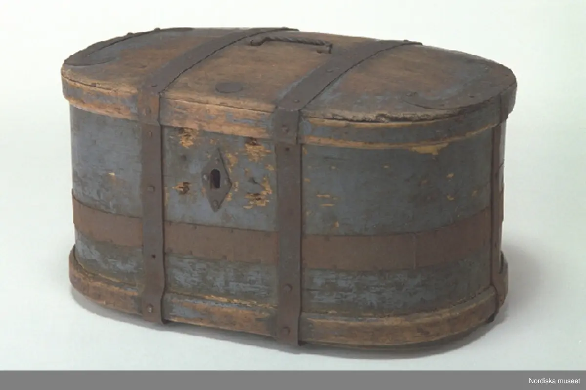 Inventering Sesam 1997-1998:
L 51, B 37, H 29 cm
Träspann, ovalt skrin, med kupigt fällock. Botten och lock av barrträ, fästade med enstaka spikar samt lim, ihopsatta av vardera två brädor, falsade. Svep av lövträ, extrasvep nedtill på bottensvepet, ihopfästade med spikar.
Järnband runtom på bottensvepet och locket, fästade runt kanterna, bottensvepet har även ett järnband som går horisontellt (förstärkning eftersom svepet spräckts), locket även med böjda järnbeslag.
Två bandgångjärn, fästade utvändigt tvärs över locket samt runt bottenkanten. Med lås, nyckel fattas, låssprint av järn i locket, romboid nyckelskylt av järn. Bygelhandtag av järn på locket.
Utvändigt målat i blått, färgen nött framförallt på locket.
Agnetha Blomberg 1998