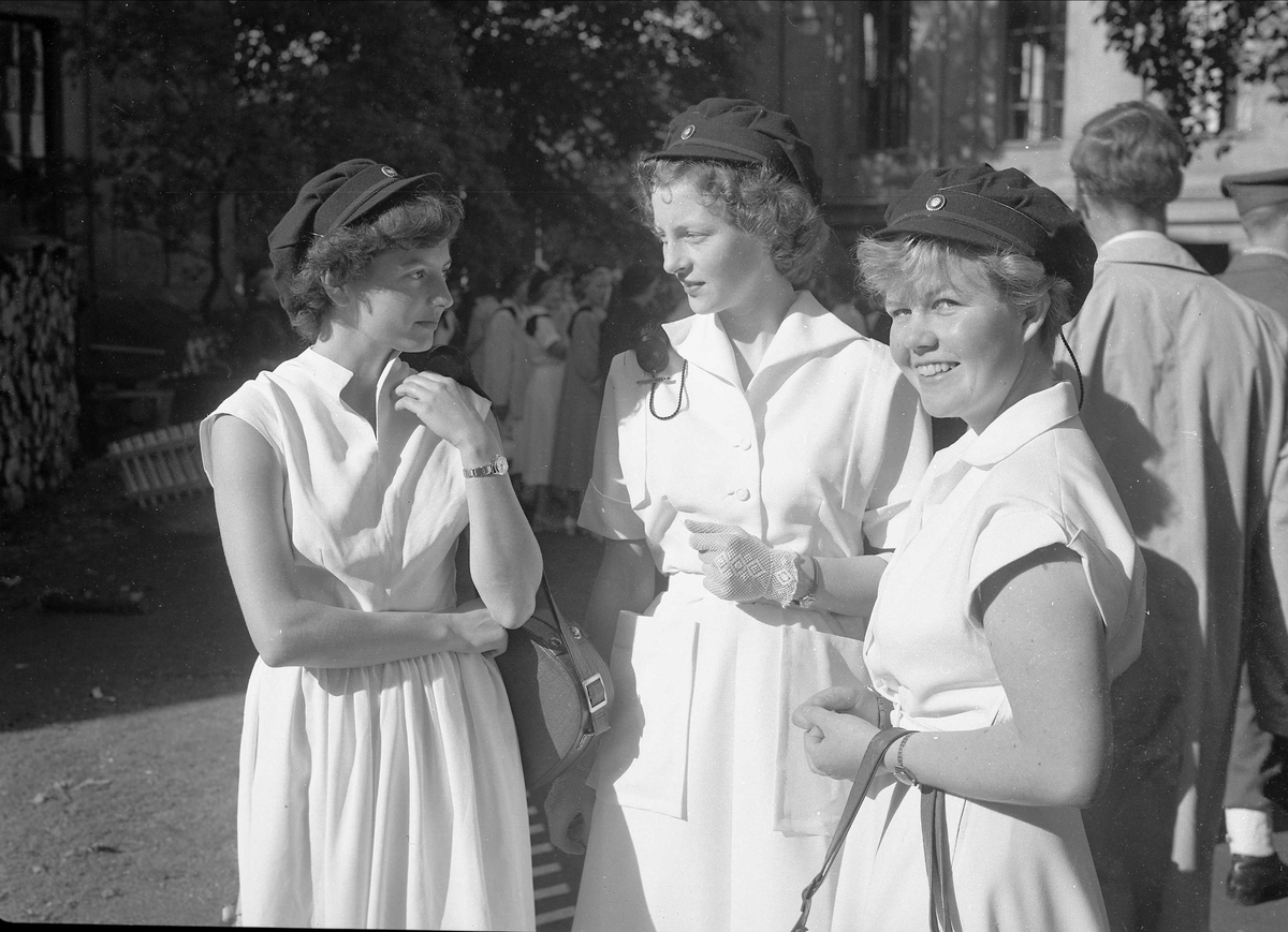 Oslo, september 1952, Universitetsplassen, immatrikulering av studenter, tre kvinnelige studenter i hvite kjoler og studentluer.