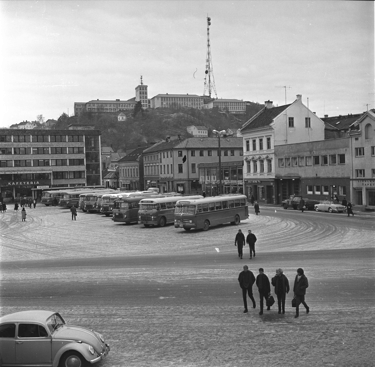 Arendal. Rutebilstasjonen med Peder Thomassons gate og Sjømannsskolen i bakgrunnen. Busser oppstilt.