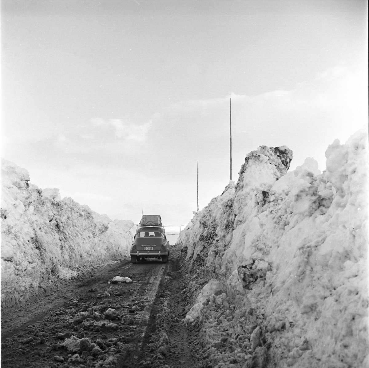 Riksvei 20, Hardangervidda, mai 1963. Veien åpnes etter vinteren. Vei med bil og brøytekanter.