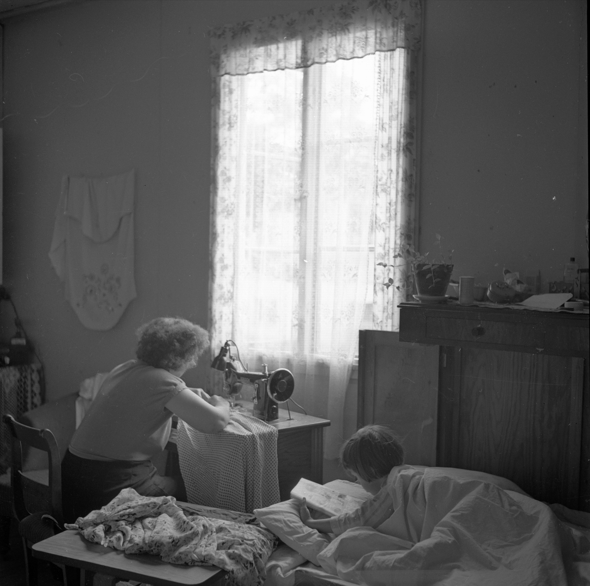 Østre Voksen, Sørkedalsveien, Oslo, 13.07.1954. Brakkeby. Interiør. Kvinne ved symaskinen.