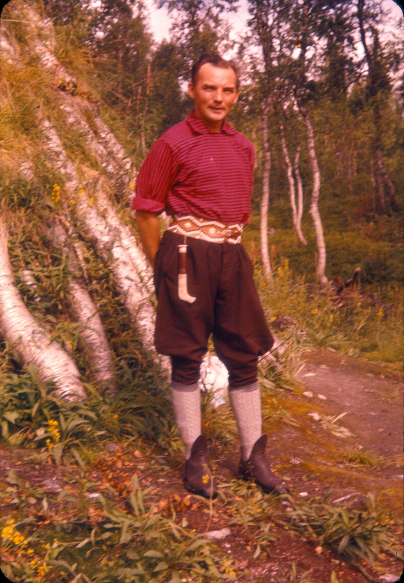 Mann med samisk belte og kniv utenfor en gamme. 1956, Namsvatnet, Røyrvik, Nord-Trøndelag.