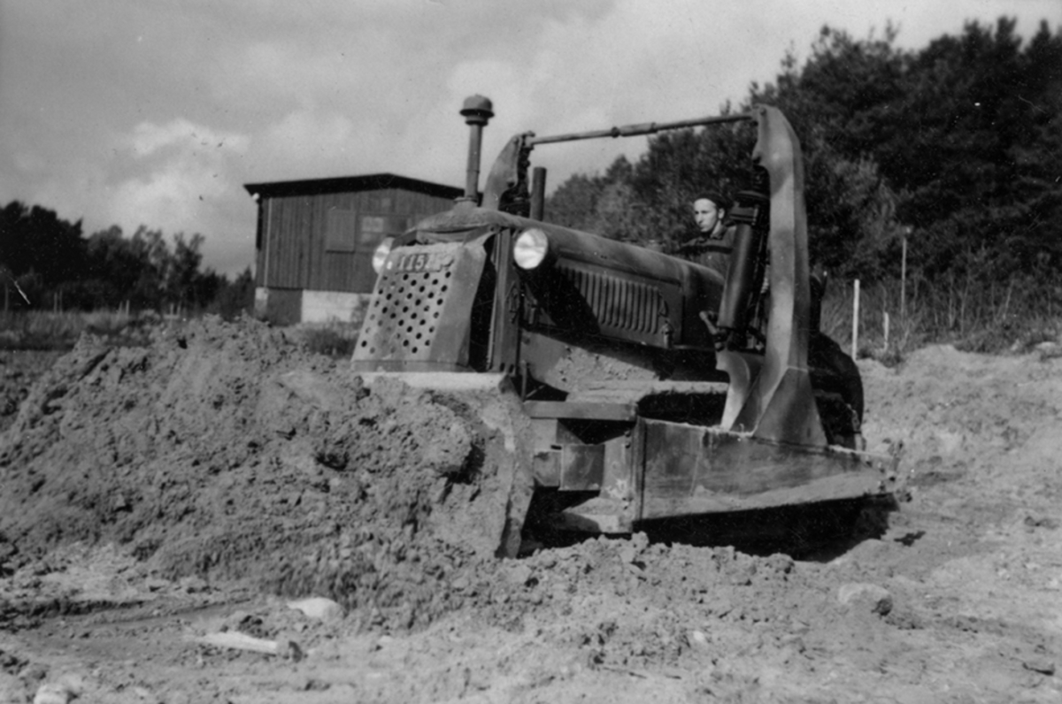 Idrottsplatsen på F 2 Roslagens flygflottilj byggs, 1943. Civilanställda tjänstemän i arbete med grävning. Människor och maskiner i arbete med grävning.