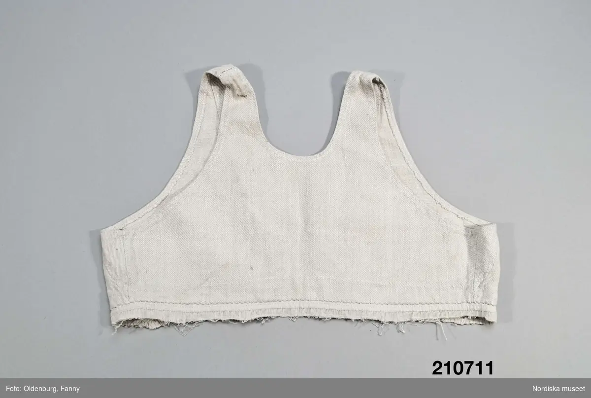 Livstycke, "bod" som varit fastsydd på en linnekjol. Av handspunnet lingarn, blångarn, i treskaftad kypert, "treskäft".  2 raka framstycken och ett ryggstycke, skarvat på axlarna, små kilar i sidsömmarna. Öppet framtill med 3 cm breda knäppkanter på båda sidorna med 2 par hakar och hyskor av mässing. Fåll nedtill med översta delen av kjolen kvar som en ring runtom, där man kan se den täta rynkningen och att kjolen varit av ett tunnare tuskaftat linne.
Denna typ av livkjol kallas i Mora och på Sollerön för vitsärk och användes sommartid. De kunde vävas mer eller mindre grova, och syddes mer eller mindre fint, släta, grovrynkade eller finrynkade och med grövre eller finare liv (bod) alltefter som man avsåg dem till grövsta vardagsbruk eller till helgdagsplagg.
Till fint hade de ofta liv av blommigt tyg men även röda eller gröna vadmalsliv förekom, de enklare hade vitt linneliv med bandgarnering. 
Vitsärkarna kom rätt tidigt ur bruk, sist var det de gamla gummorna, som nyttjade dem. Få är bevarade, ty det var vanligt att kvinnorna sveptes i dem.
Se Ella Odstedt: Folkdräkter i övre Dalarne sid 194-195.

Jfr. hel livkjol från Sollerön inv.nr 211804.
/Berit Eldvik 2007-09-21