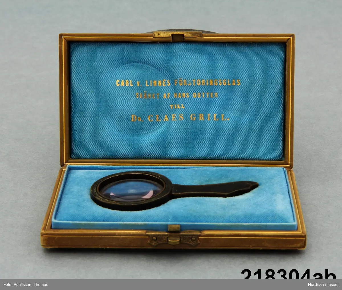 Huvudliggaren:
"a-b Förstoringsglas, runt, ram av horn, handtag av horn; i yngre etui; ljusbrunt skinn med Linnea, fällock; sign. 'F Beck & son Stockholm'; med guldtryck i locket: 'Carl v. Linnés förstoringsglas skänkt af hans dotter till Dr Claes Grill'. G[åva] 23/5 1939 av överstinnan Maria Grill, f. Reuterskiöld, Stockholm."