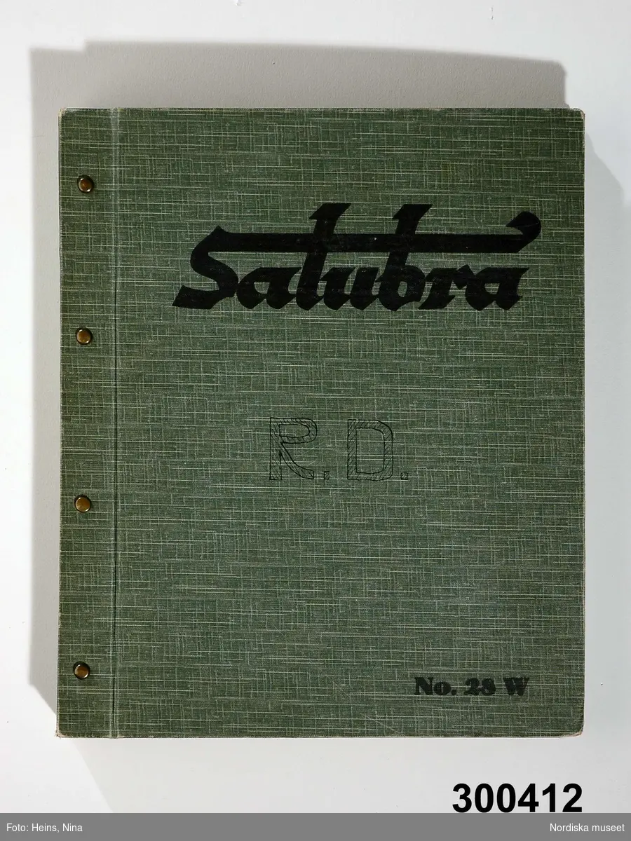 Huvudliggaren:
"Tapet, provbok, papper; 114 enfärgade tapetprover, tvättbar tapet, märke 'Salubra'; omslag plastbehandlat grönt och vitt tyg; små provbitar klippta från en del av proverna; från firma Ingeniör Robert Dahlström, Sveavägen 25-27, Stockholm. Br 26 cm, H 31 cm."

Katalogkort:
Ingen ytterligare information utöver huvudliggaren.

På framsidan står skrivet ägarens initialer med handskrift samt på insidan av pärmen finns en adress stämpel gällande ägaren. . Första sidan med gulnad reklamtext etikett. 
Anm: Mindre användnings slitage.
/Cecilia Wallquist 2007-02-12.