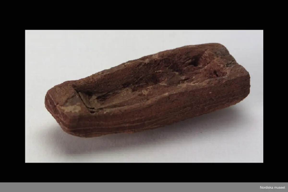 Inventering Sesam 1996-1999:
L 4,7 cm
B 2 cm
H 1 cm
Leksaksbåt täljd i bark. Tvärt avskuren i för och akter, flat botten.
Har täljts av Gunnar Hazelius (1874-1905, son till Skansens och Nordiska museets grundare Arthur Hazelius).
Bilaga
AT 1987 [=Annika Tyrfelt]
Tallbark.