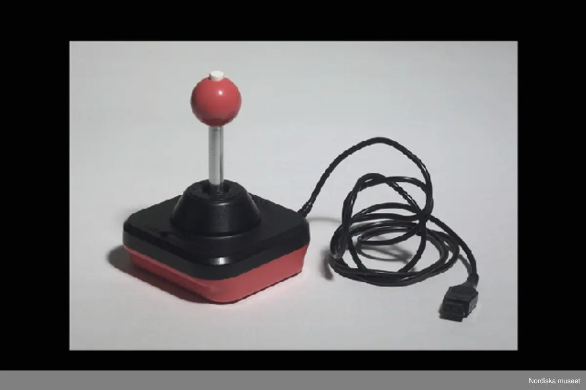 Inventering Sesam 1996-1999:
L 11 cm
B 11 cm
H 15,5 cm
Joystick till dataspel. Lådformig, r¿d botten och svart ¿verdel, mitt på rund upph¿jning med spak med skaft av kromad metall och r¿d kula med vit knapp upptill. På den svarta ¿verdelen r¿d knapp och svart på- och avstängninsknapp. Svart fast sladd med kontakt. Undertill märkt "WICO / COMMAND CONTROL / MADE IN USA / PAT: PEND".
Med joysticken sk¿ter man figurer/bilar/rymdskepp eller dyl. på TV-skärmen när man spelar dataspel.
Axel Brundin (f¿dd 1977) fick datorn i julklapp. Den var k¿pt från pojkarna Norman (f¿dda 1971) som tidigare använt den.
Dataspel och tillh¿rande f¿remål; Tangentbord ivn.nr 321.617 kasettbandspelare inv.nr 321.618, transformator inv.nr 321.619, Kasettväska med kasettband med olika dataspel inv.nr 321.620:1-24, tre joy sticks inv.nr 321.621 och 321.622, skokartong inv.nr 321.623 (i vilken kasettband f¿rvarades)  och Kasettband med spel 321.624-321.639
Instruktionsb¿cker, band- och kundf¿rteckning finns på arkivet.
Bilaga
EB 1995 [Elisabet Brundin]
Leif Wallin 1998
