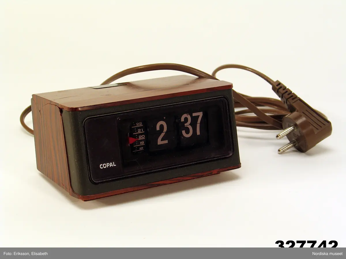 Huvudliggaren:
"Väckarklocka, elektrisk, plast. Fyrkantig, brun träimitation, rökfärgat glas, vita digitala siffror. Tillv. Copal, Japan ca 1970. gåva av anonym givare som utsatts för sexuella övergrepp som barn på 1960-70-talet, då hon kunde se klockan nattetid. H 7,5, L 14, B 10 cm. Fast sladd. Spricka på undersidan. G 29/9 2000 Anonym givare pseudonym Gertrud."

Bilaga:
"Gertruds" berättelse om klockan.
