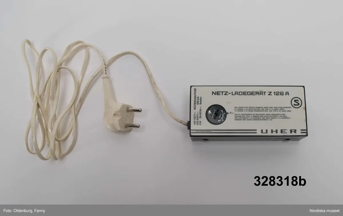 a-g:
Bärbar bandspelare för rullband. Metall, rektangulär, grå eloxerad, tangenter, vred på långsidan, fönster med ljudskala, varvräknare. Spole, mikrofon, mikrofonstativ, bruksanvisning. Batteri- och nätdriven, laddningsbar.
Tillhörande brun läderväska, axelväska med bred rem, ficka för bruksanvisning, mikrofonfack, konstmaterialfoder, uppknäppbar framsida, fällock med spännen. Adresslapp handskriven med förste intendet Göran Rosanders handstil.

a+) Bandspelare
b) Batteriladdare med sladd
c) Mikrofon med sladd
d) Mikrofonstöd
e) Intruktionsbok
f) Kopplingsschema (papper)
g+) Väska.

Den bärbara Uher-bandspelaren innebar en revolution för fältarbete. Fältarbetaren var inte enbart hänvisad till papper och penna. På 1970-talet fanns till en början endast en bärbar bandspelare. Fältarbeten planerades efter tillgänglighet till bandspelare. Samtliga avdelningar samsades till en början om dennna.
/Heidi Henriksson 2005-10-11