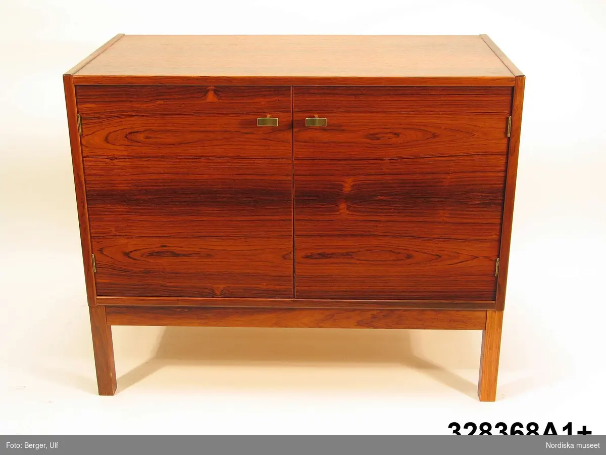 a-e:
Bokhylla, "Excellent",  med TV-bänk samt bar- och vitrinskåp, jakarandafaner på spånskiva, IKEA, 1968. 

Hyllan består av fyra sektioner med hyllor löst placerade på underredet. Skåp- och byråunderdelar med ryggar av masonit, fastnitade. Kvadratiska ben, fastskruvade i underredet. Lådsidor m.m. av björk och lådbottnar av vitlackerad masonit. Flyttbara hyllplan. Draghandtag och gångjärn av mässing.  Enligt IKEA-katalogen 1968 är ytan plastbehandlad.

Hyllan uppställd, från vänster till höger:
a:1+) Skåp med två dörrar samt a:2+) hyllöverdel, ett fast och två flyttbara hyllplan. Överst vitrindel med två skjutdörrar av glas (höjd 53,5 cm, bredd 41,5 cm).
b:1+) Byrå med tre lådor samt b:2+) hyllöverdel med tre flyttbara hyllplan. 
c:1+) Tv-bänk med en låda samt c:2+) hyllöverdel med tre flyttbara hyllplan.
d:1+) Skåp med två dörrar samt d:2+) hyllöverdel med 1 flyttbart hyllplan. Överst vitrindel med två skjutdörrar av glas (höjd 53,5 cm, bredd 41,5 cm), därunder ett barskåp med spegel som bakvägg, utrymme för flaskor till vänster och två glashyllor (48 x 19,5 cm) till höger. Barskåpet med fällbar klaff med lås. Belysning monterad i skåpets överkant.
e) Nyckel till barskåpets klaff. L 4,3 cm.

Möbeln har använts av givarinnan, Berith Helldén, f. 1945, hemmafru, och hennes man, Lars-Göran Helldén, f. 1946, inköpare, Tungelsta. Paret gifte sig 1967 och bodde som nygifta i en liten lägenhet i Borås. När de fick möjlighet att flytta till en större lägenhet i samma stad, utökades vardagsrumsmöblemanget. Hyllan inköptes 1968 på IKEA i Älmhult. Enligt IKEA-katalogen 1968 kostade de fyra hyllsektionerna totalt 2484 kronor. Hyllan har använts som förvaringsmöbel i vardagsrummet i Borås och i familjens nuvarande bostad i Tungelsta fram till våren 2005, då den inköptes av museet.

Hyllans innehåll har dokumenterats och en utförlig intervju med Berith Helldén har gjorts 2005-05-09 (se arkivreferens).
/Anna Womack 2005-10-18
