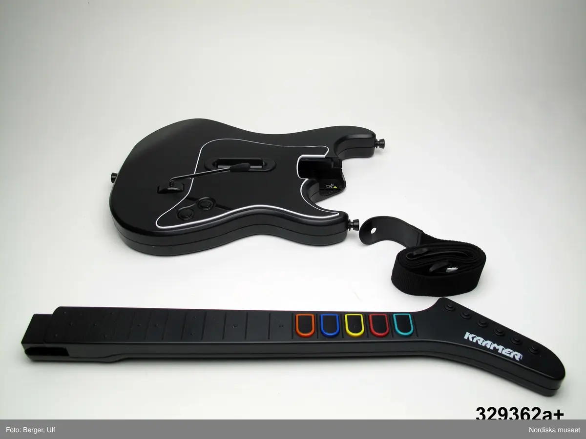 TV-spelet "Guitar Hero III Legends of Rock" med förpackning. 
a+) Elgitarr med avtagbar hals, av svart plast, svart axelrem av syntettextil med konstläder (plast) och plastöglor.
b+) 2 ark med klisterbilder att fästa på gitarren
c) Broschyr med instruktioner om funktion och säkerhet på flera olika språk.
d) Fodral av blå plast med inplastat omslag av papper med text. På framsidan "Playstation 2 / Guitarr Hero III LEGENDS of ROCK" och bild på hårdrockare. Baksidan bl.a. "SLÄPP LOSS DIN INRE ROCKLEGEND / Över 70 rockiga låtar.".
e) CD-skiva med programvara (förvarad i fodral d).
f) Instruktionsbok på de nordiska spårken (förvarad i fodral d) 
g+) Förpackning av papp. Ytterfodral med text och bilder. Inre lådan med inredning för de olika delarna.
 
Tv-spelet är avsett för spelplattformen Playstation 2, vilket är en vanlig spelplattform. Spelet går ut på att det spelas upp en låt (man väljer själv låt och nivå) och ska sedan försöka spela på gitarren genom att trycka på knapparna och på så vis lyckas spela samma ton som musiken spelar samtidigt.

Vid förvärvet avlägsnades plastpåsar som del av a och b låg i, samt två 1.5volts-batterier av märket Duracell som låg i gitarren, då de ej bedömdes möjliga att spara. Även fyra papperspåsar med Silicagel (för att hindra att fukt skadar elektronik mm) togs bort.

Nyinköp den 2008-02-20 för att rekonstruera julkklappsönskemål julen 2007 från Erik Thomelius född 1999, Vaxholm. Inköpt av Nordiska museet för 439 kr. Ingår i projektet "Barn tar plats". Se dokumentation i arkivet D455.
/Ulf Hamilton 2008-05-27     
