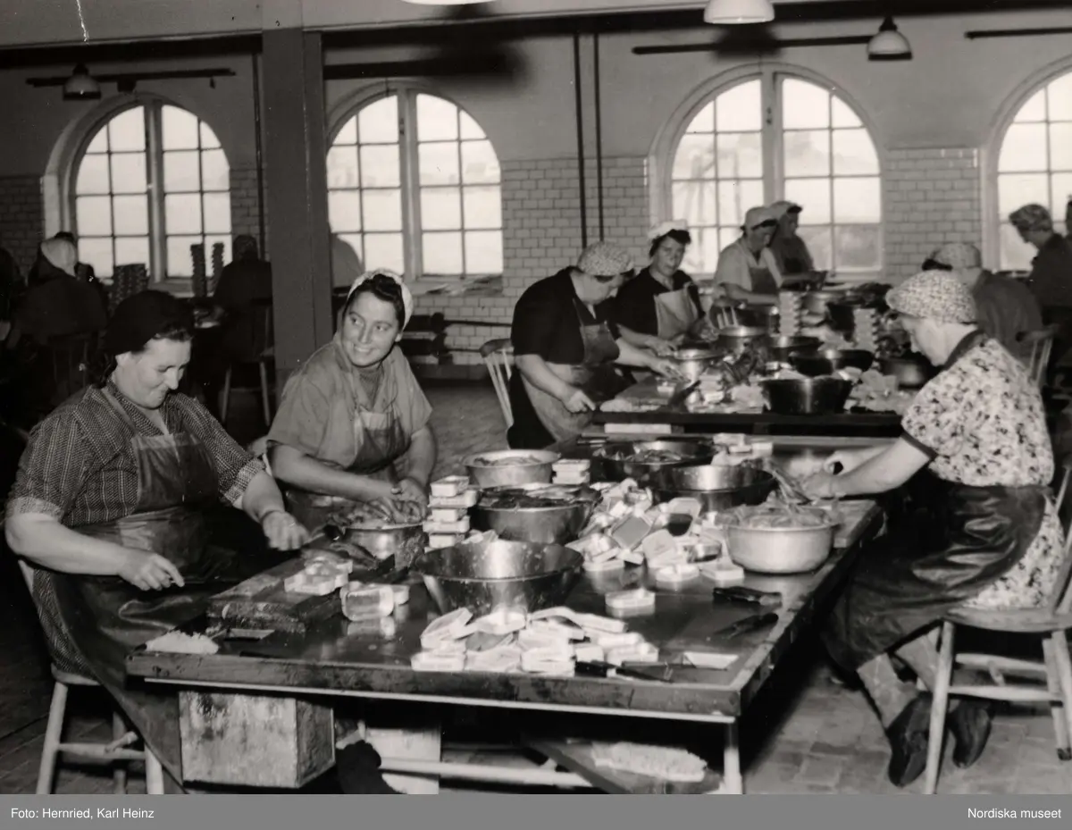 Sveriges Förenade Konservfabriker, AB i Lysekil, Bohuslän. Bolaget  grundades 1898 och förfogar över åtta fabriker. I Lysekil har man specialiserat sig på enbart sill- och ansjovisinläggningar samt kryddning och sockersaltning av skarpsill och sill. Produkterna går under namnet "Fyrtornet". 
Kvinnor sitter vid stora arbetsbord och rensar och skär fisk som de sedan lägger på burk