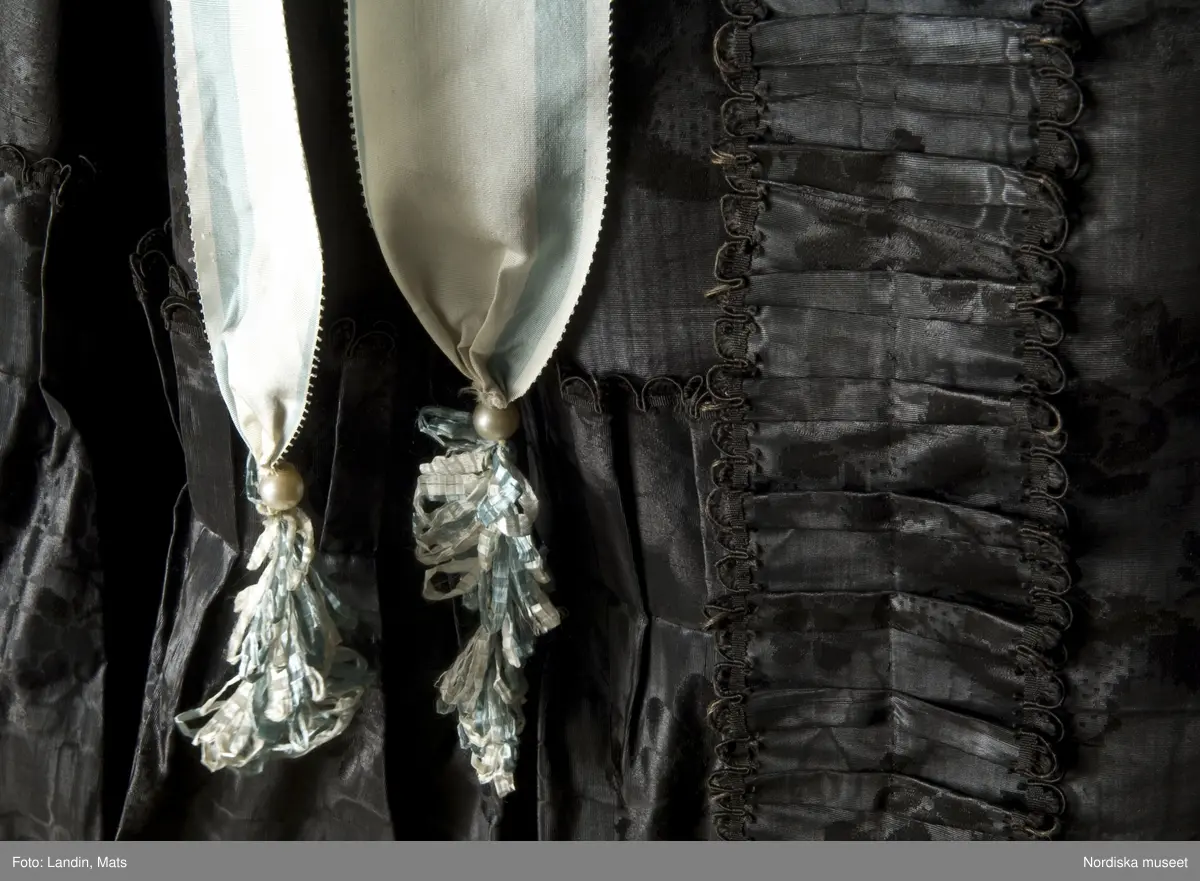 Bruddräkt, svenska dräkten. Av svart mönstrat siden. Buren 1 januari 1780 av Sofia Lovisa Brüch. Nordiska museet inv nr 192119.