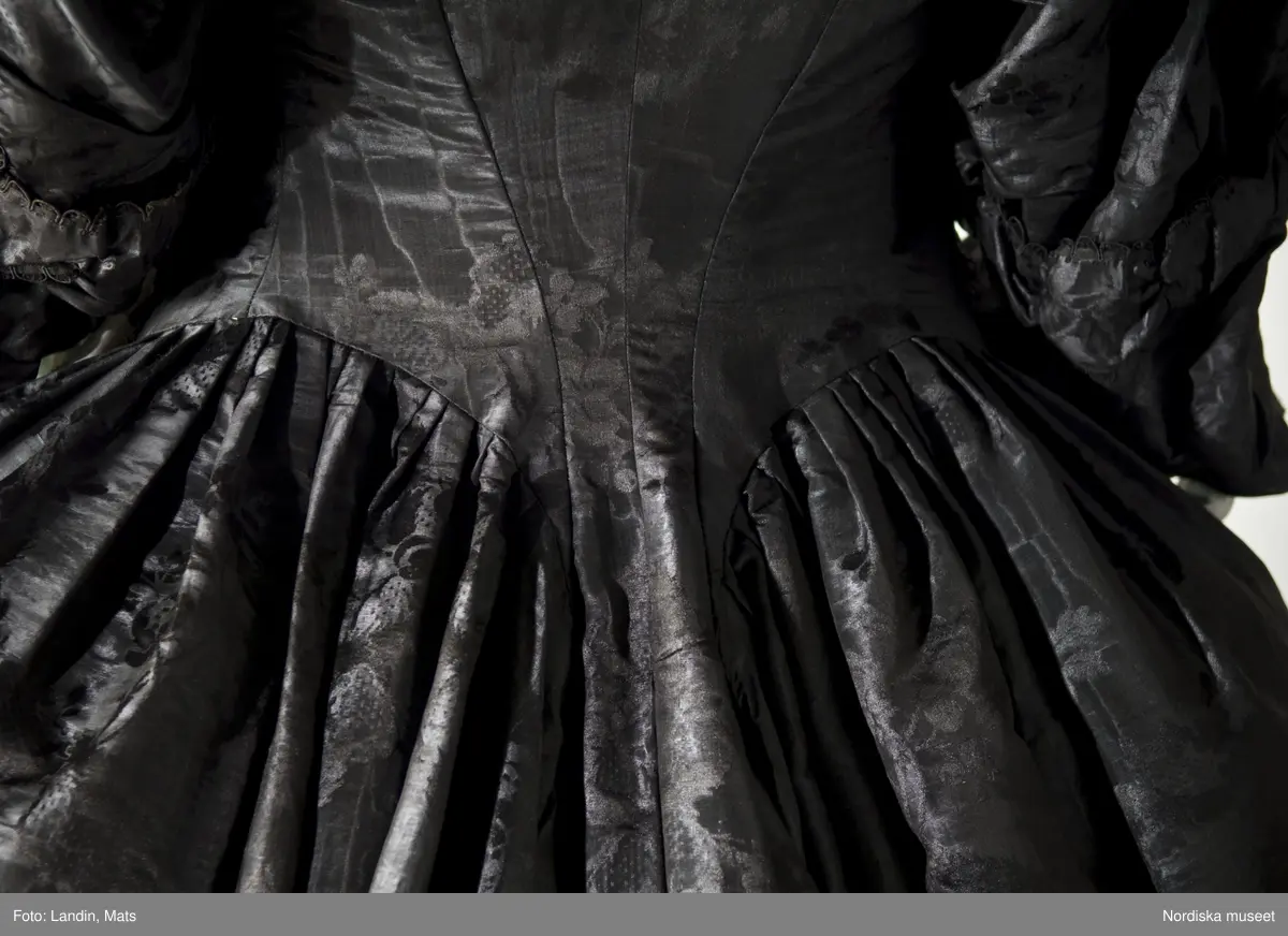 Bruddräkt, svenska dräkten. Av svart mönstrat siden. Buren 1 januari 1780 av Sofia Lovisa Brüch. Nordiska museet inv nr 192119.