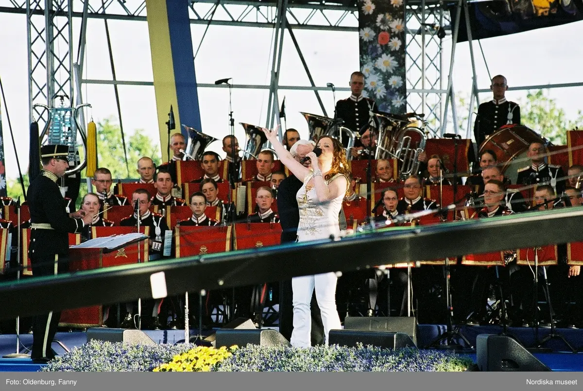 Firandet av den svenska nationaldagen den 6 juni 2004 på Skansen, Stockholm. Den kungliga familjen. Orkester. Publik. Artisterna Jan Malmsjö, Shirley Clamp, Magnus Carlsson.