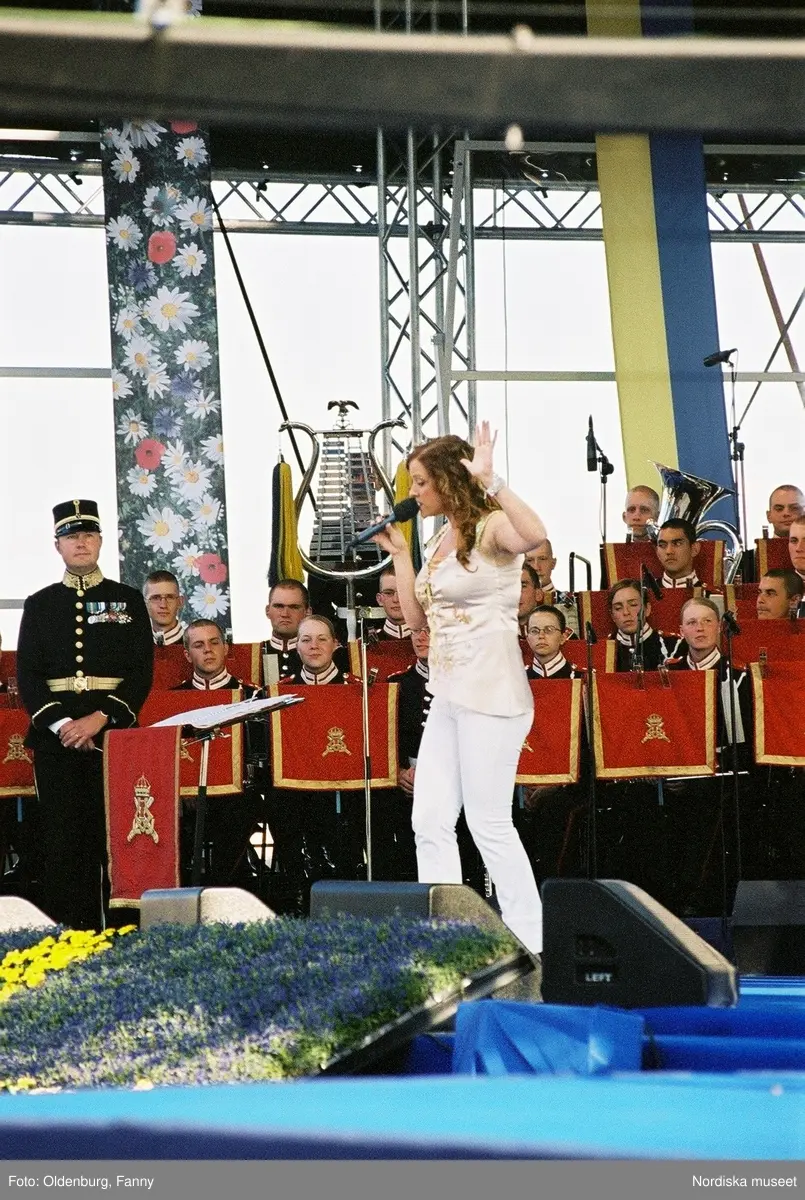 Firandet av den svenska nationaldagen den 6 juni 2004 på Skansen, Stockholm. Den kungliga familjen. Orkester. Publik. Artisterna Shirley Clamp, Tomas Ledin och Lasse Berghagen. Programledaren Agneta Bolme Börjefors.