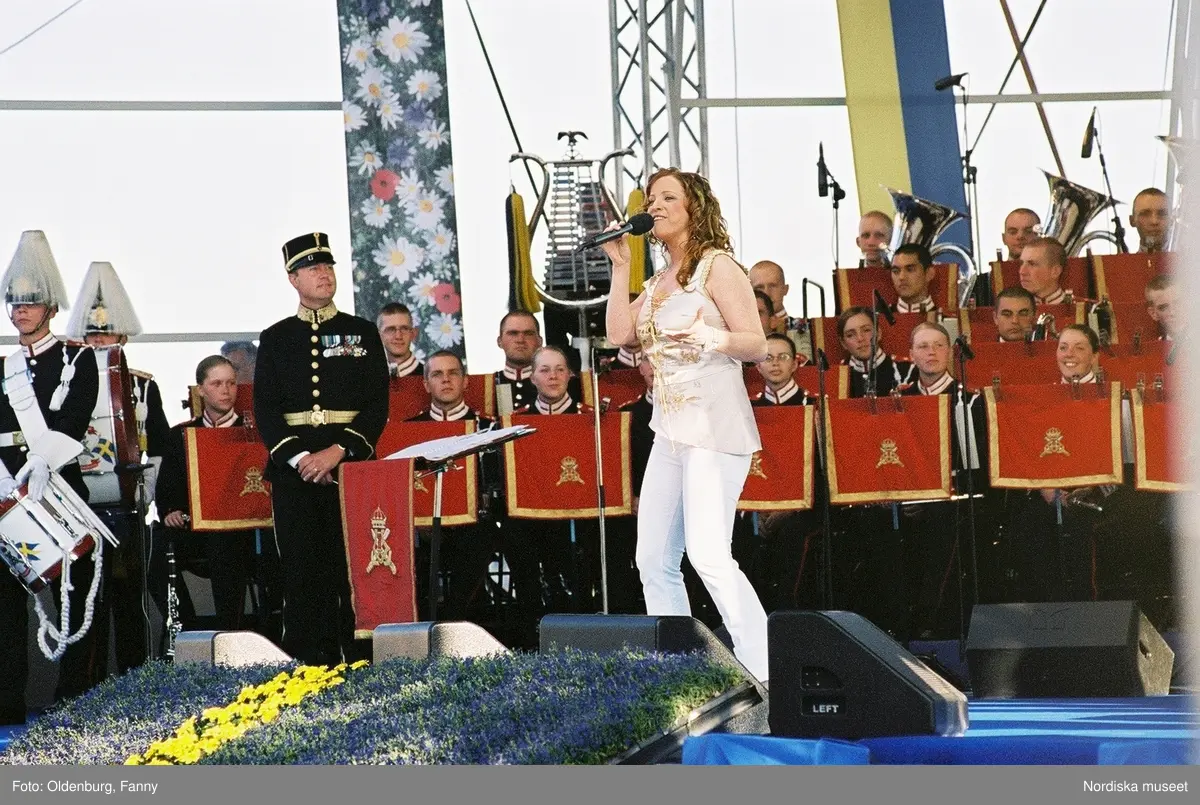 Firandet av den svenska nationaldagen den 6 juni 2004 på Skansen, Stockholm. Den kungliga familjen. Orkester. Publik. Artisterna Shirley Clamp, Tomas Ledin och Lasse Berghagen. Programledaren Agneta Bolme Börjefors.