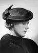Kvinnlig modell i svart balibuntalhatt med garnering av svart grosgrain-band. Nordiska Kompaniet, Stockholm.