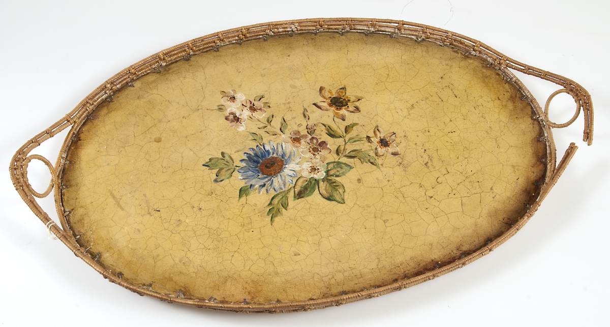 Bricka. Oval. Tillverkad av Gertrud Nilsson. Botten av masonit, på översidan målad med oljefärg, gul krackelerad bottenfärg med blomsamling i mitten i blått, grönt, vitt, brunt och rött. Kant bunden av björkrötter som även bildar handtag på var sida.