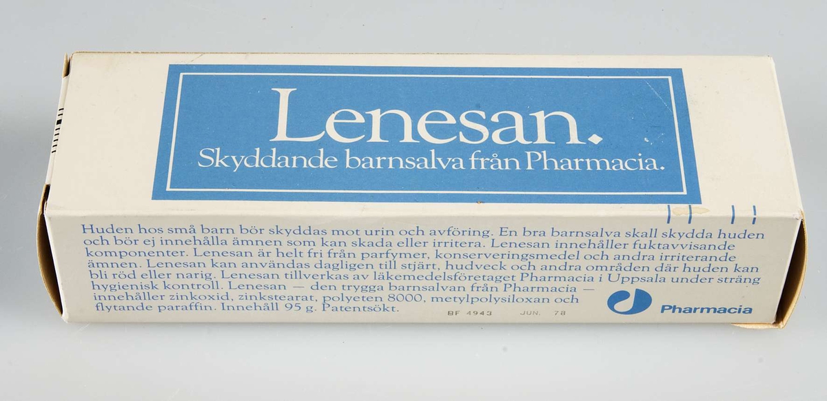 Ask av vitt papper med text i ljusblått och vitt "Lenesan. Skyddande barnsalva från  Pharmacia". I asken vit och ljusblå tub med samma text.