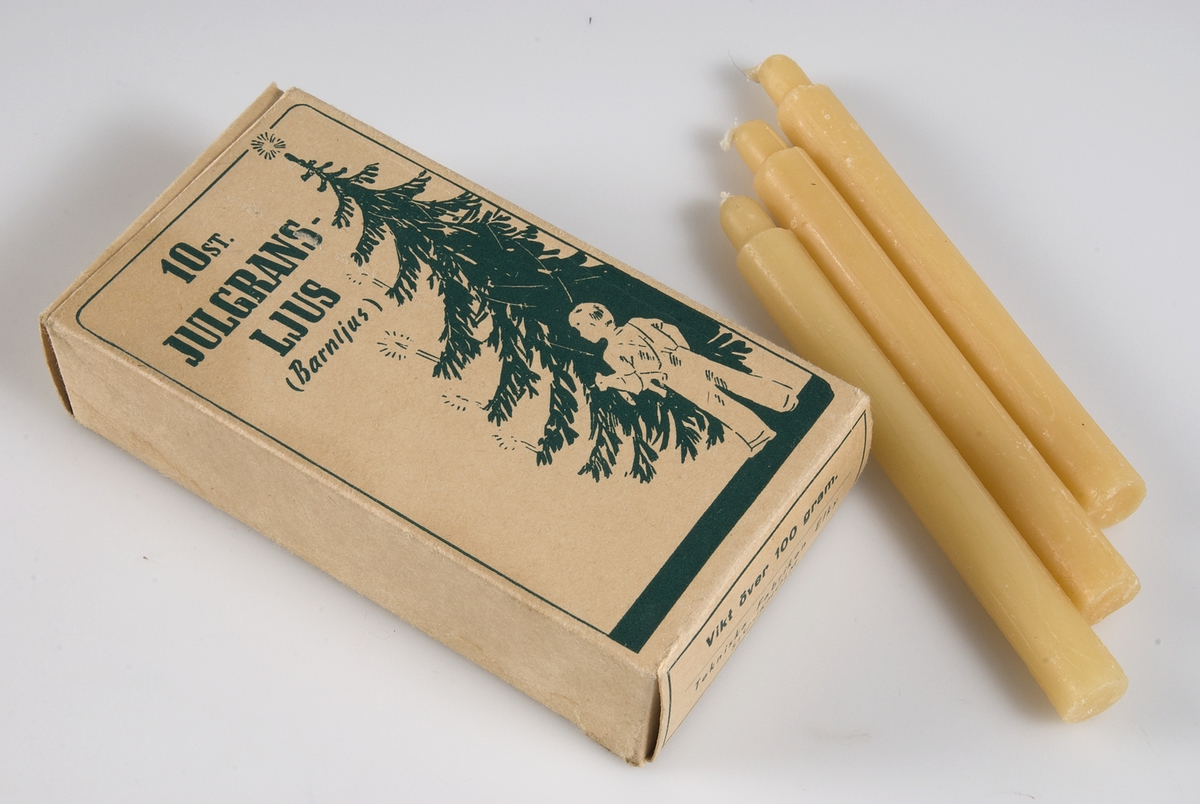 Två kartonger av brunbeige papp med grönt tryck, bild av julgran och ett barn och text: 10 st JULGRANSLJUS, (Barnljus), Tekniska Fabriken Elky, Stockholm. Innehåller 10 gulvita stearinljus. 