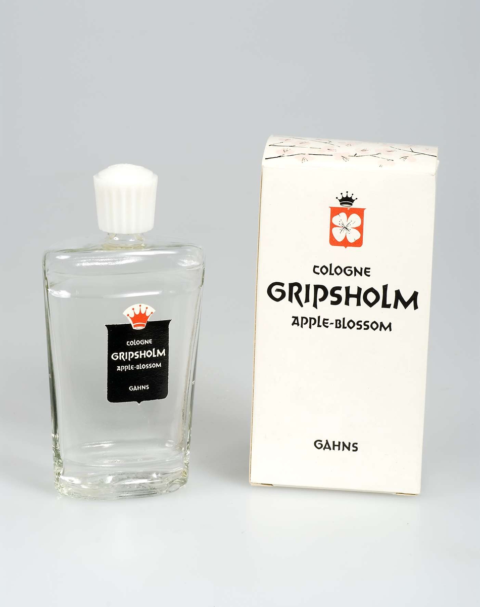 Oöppnad förpackning. Flaska av ofärgat glas med skruvlock av vit konstmassa, refflad, med tillverkarnamnet i relief. Liten etikett av svart papper med text: COLOGNE GRIPSHOLM APPLE BLOSSOM. I förpackning av vit papp med tryckt dekor på kortsidan och på locket i form av rosa äppelblom, och text i svart som ovan.