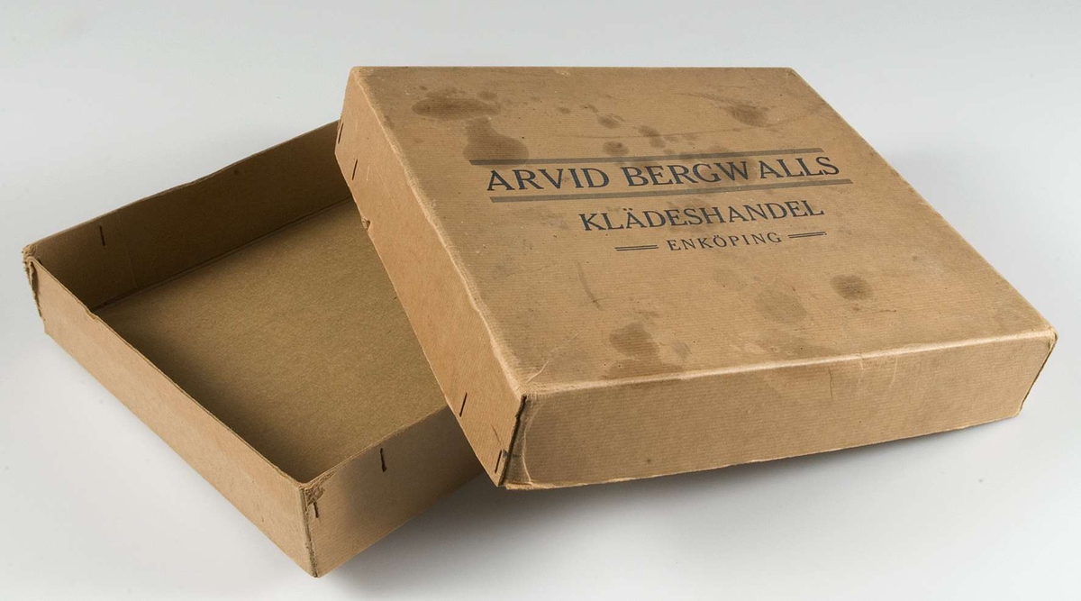 Nio häften med typgrover i kartong av brun papp. Kartongen märkt med blått tryck: ARVID BERGWALLS KLÄDESHANDEL, ENKÖPING. Alla häften märkta med tryck: ARVID BERGWALL, ENKÖPING. Åtta häften har omslag av vävimiterande papp, tre i brun färg och fem i grön färg. Ett häfte med omslag av papp i orangegul färg. Alla häften innehåller tygprover uppklistrade på pappark. Under tygproverna finns en svart ram och svart tryck med artikelnummer, tygbredd, pris och typ av tyg.
Häfte 1, svart tryck: STAPELVAROR i Skotska kostymtyger.
Häfte 2, svart tryck: NYHETER för Vår- & Sommarsäsongen 1928, Kostymtyger, Häftet 3.
Häfte 3, svart tryck: NYHETER för Vår- & Sommarsäsongen 1941, Klänningstyger, Bomullstyger och Fodervaror, Häftet 4.
Häfte 4, svart tryck: NYHETER för Vår- & Sommarsäsongen 1940. Bomullstyger och Fodervaror, Häftet 6.
Häfte 5: NYHETER för Höst- och Vintersäsongen 1941 - 42, Herrvaror, Häftet 1.
Häfte 6: NYHETER för Höst- och Vintersäsongen 1941 - 42, Skinnimitationer och Skidmilton, Häftet 2.
Häfte 7: NYHETER för Höst- och Vintersäsongen 1941 - 42, KAPPTYGER, Häftet 3.
Häfte 8: NYHETER för Höst- och Vintersäsongen 1941 - 42, Klänningstyger, Häftet 4.
Häfte 9: NYHETER för Höst- och Vintersäsongen 1941 - 42, Klänningstyger, Bomullstyger och Fodervaror, Häftet 5.