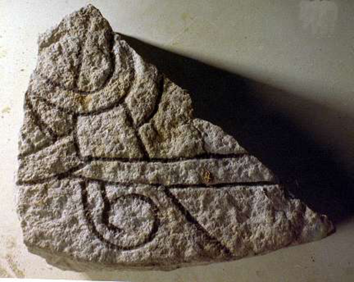 Runstensfragment med runslinga på två sidor, röd- och svartmålade. Inskrift  A: "...ina  x  fitiR...", "  B: "...ur  x  ...a x k...", (= ... denna (sten) efter...).