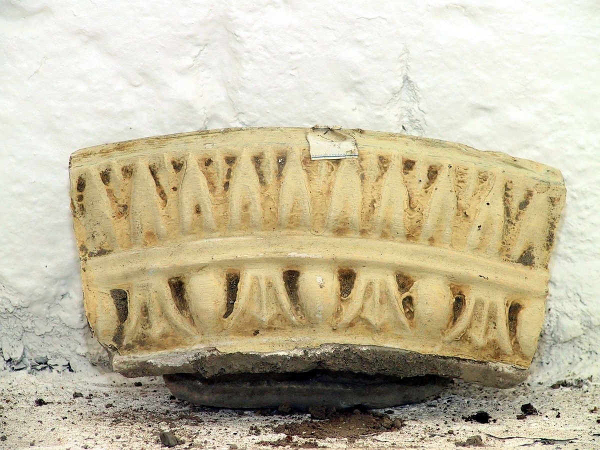 Kakel till rund kakelugn, målade med svagt gul och turkos färg. 45 hela kakel, 35 delar av kakel samt 26 delar till över- och/eller undersims. Vissa av kaklen har märkts med etikett med blå tunn ram.