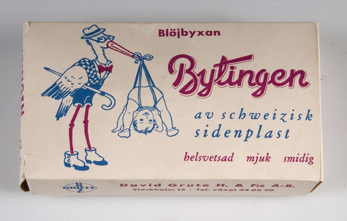 Blöjbyxa av plast i kartong av papper. Tryck i blått och rött, text om blöjbyxan, bland annat:  Blöjbyxan Bytingen av schweizisk sidenplast... samt David Grute H. & F:s A-B, Stockholm 15...