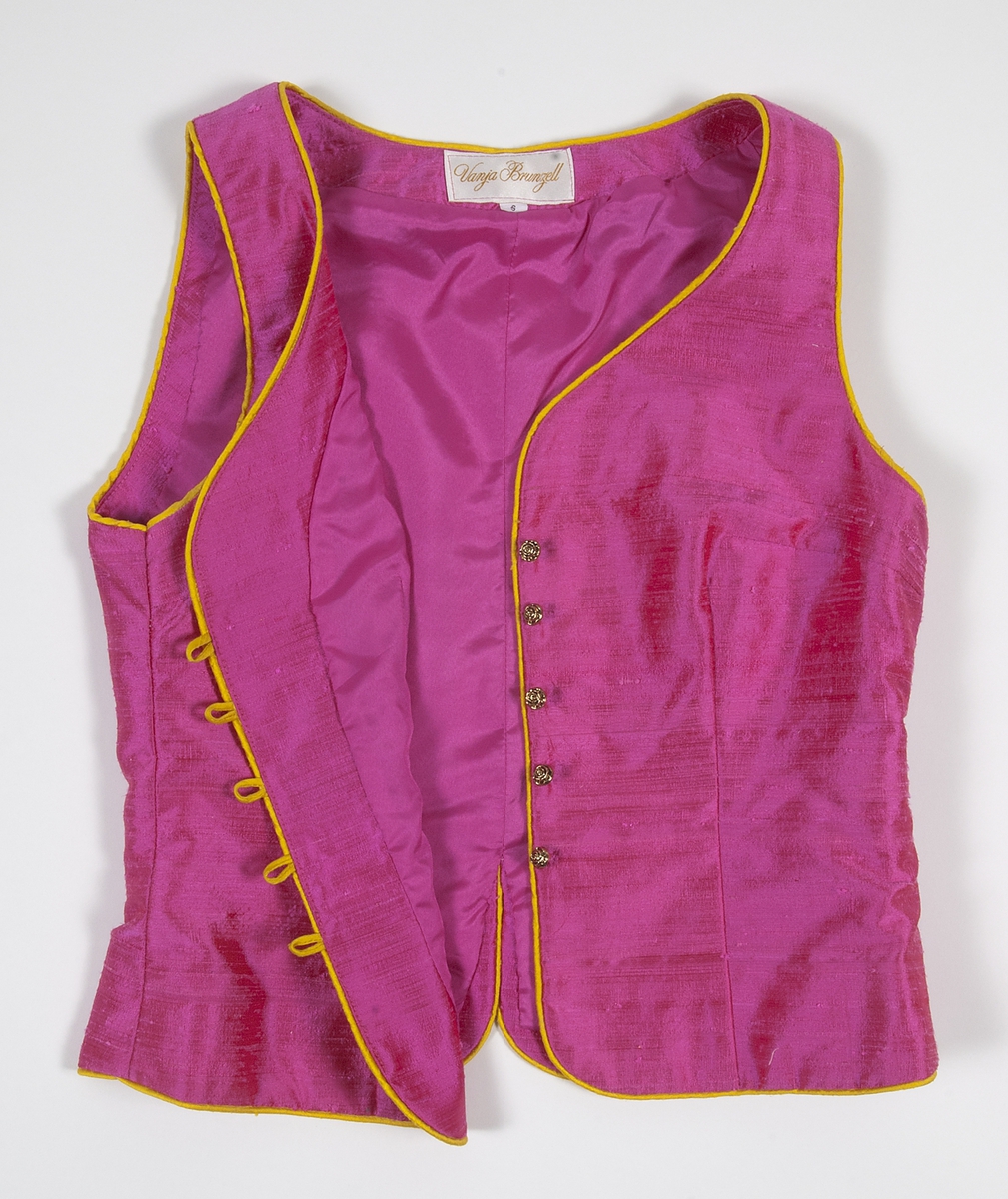 Ärmlöst liv i rosa siden. Livet är formsytt och kantat i gult siden. Livet knäpps på framsidan med agraffknäppning med fem guldfärgade plastknappar som har formen av rosor. Dessa är knäppta med agraffknäppning med öglor i gult siden.Livet är fodrat med rosa fodertyg.