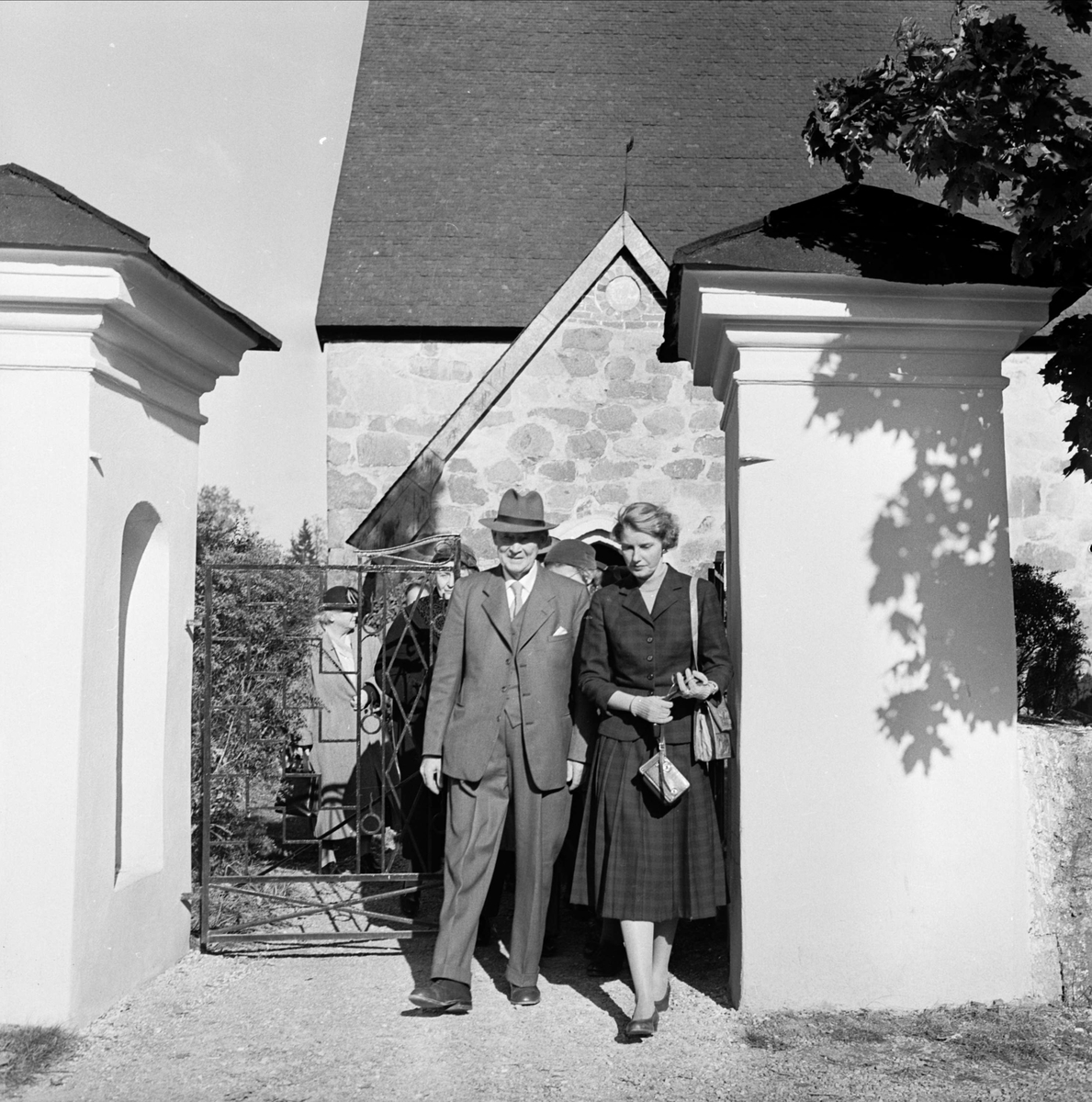 Anna-Märta Berg och äldre man utanför Morkarla kyrka, Uppland i samband med Upplands fornminnesförenings höstutflykt 1956