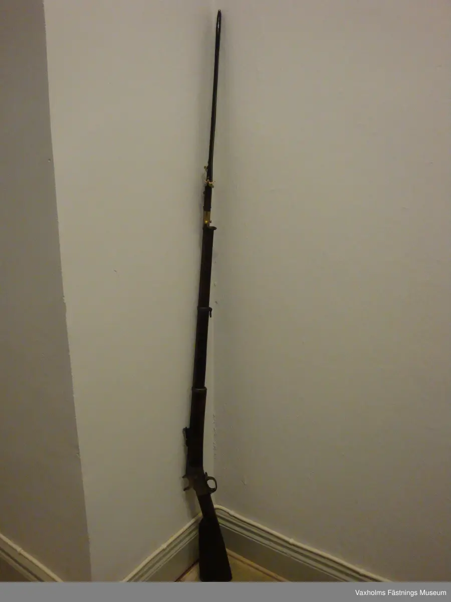 1867 års gevär m/1868 med sabelbajonett och balja.
Stock och kolv med hals i två delar, sammanhållna av mekanismen. Kolvens vinkelsättning mot kärnlinjen stor. Mörkbrunbetsad. Bakplan insvängt. Beslagen av järn. Näsband och två pipband. Ränna för laddstake som saknas. Pipa rund, avsmalnande mot mynningen, brungjord. 6st refflor. Korn och uppfällbart sikte med skala. Klack för bajonett. Slaghane och stötbotten med krusst grepp. 
I.F. 35d. I.G.I.