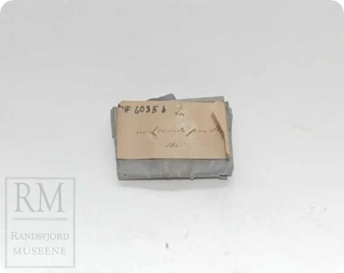 a: Liten dukke i stoff. Flatklemt. To underskjørt, skaut. b. Papir med håndskrift stilet til "Student Nielsen" og merket "Fra en Venninde paa Røros 1865" Tekst: Agtværdige Herr Person! Saasom, dasom og eftersom jeg i disse Dage er berøvet mine fordums gode Talegaver maa jeg i dets Sted gribe til Pennen, for paa den Maade, at faa sige Dem, hvad som egentlig ligger mig paa Hjerted. Det er blit mig fortalt, at De om nogle Dage, agtes at drage ned til Hovedstaden. Den samme Tour staar ogsaa for mig, men at jeg alene kan begive mig afsted skjønner De nok er en Umulighed. Derfor kjære Student, er det min inderlige Bøn til dem, om jeg kan faa slaa Følge med. Jeg ser dem an for at være en ret paalidelig og god Reisefælle, og vover jeg da at gjøre Dem dette Spørgsmaal. Haaber da at De unskylder min Nærhed, slutter jeg disse Linier. Det er mig meget om at gjøre at jeg allerede i Dag kunne faa et par Ord til Svar. Modtag den bedste Hilsen fra Deres hengivne og forbundne Simonette"