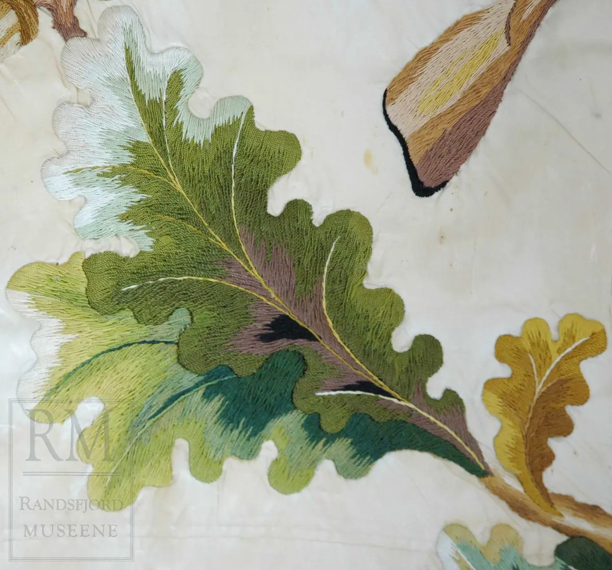 Fane av hvit silke. Løpegang på den ene siden har revnet. Brodert tekst, samt eikebladskrans med sløyfe omkring to gevær med påhengende krutthorn.