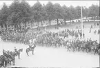 Parad på Gustaf V:s födelsedag 1928. Förbimarsch för platschefen överste Reuterswärd på skolplan framför Eric Ugglas skola. I bakgrunden till vänster milostabsbyggnaden.