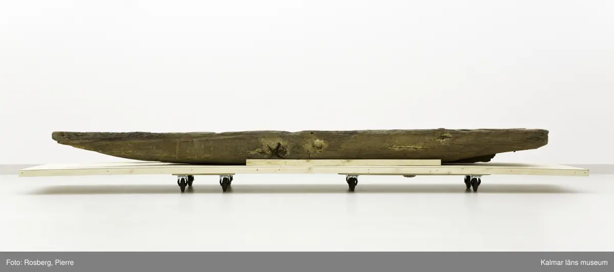 KLM 45167. Båt, stockbåt. Av urholkad trädstam. Huggen i ett stycke. Rektangulärt, något fallande tvärsnitt. Sprucken i fyra delar men de kan lätt sättas samman. I aktern en köl som saknar partier. Kölen sträcker sig fram mot toften, sittbrädan, i båtens akterdel. I toften ett borrat hål. I bottnen på styrbord sida ett hål med en träplugg i, likaså babord reling har ett sådant hål. Fören har blivit lagad vid någon tid och ett stort stycke saknas. I akterns ände tre borrade hål men träpinnar i. Små borrade hål och lagningar med järndobbar, framför allt i fören.