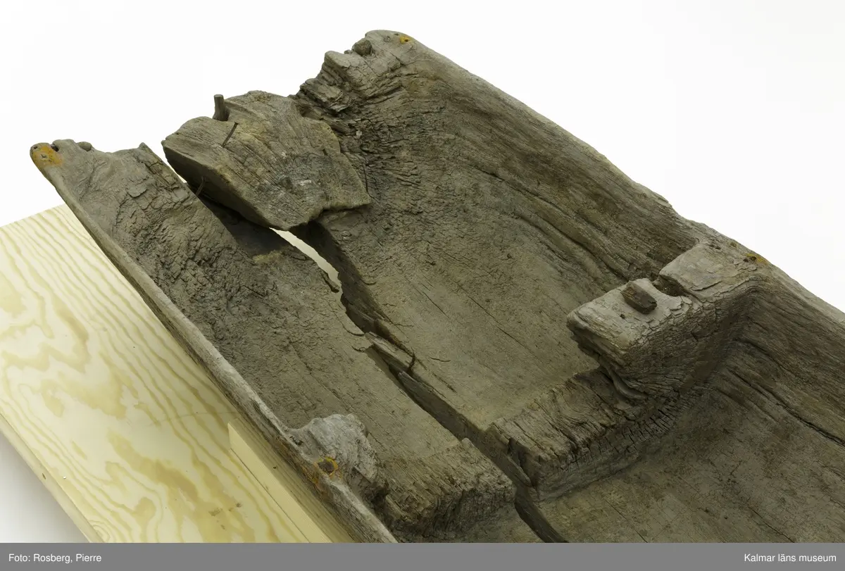 KLM 45167. Båt, stockbåt. Av urholkad trädstam. Huggen i ett stycke. Rektangulärt, något fallande tvärsnitt. Sprucken i fyra delar men de kan lätt sättas samman. I aktern en köl som saknar partier. Kölen sträcker sig fram mot toften, sittbrädan, i båtens akterdel. I toften ett borrat hål. I bottnen på styrbord sida ett hål med en träplugg i, likaså babord reling har ett sådant hål. Fören har blivit lagad vid någon tid och ett stort stycke saknas. I akterns ände tre borrade hål men träpinnar i. Små borrade hål och lagningar med järndobbar, framför allt i fören.