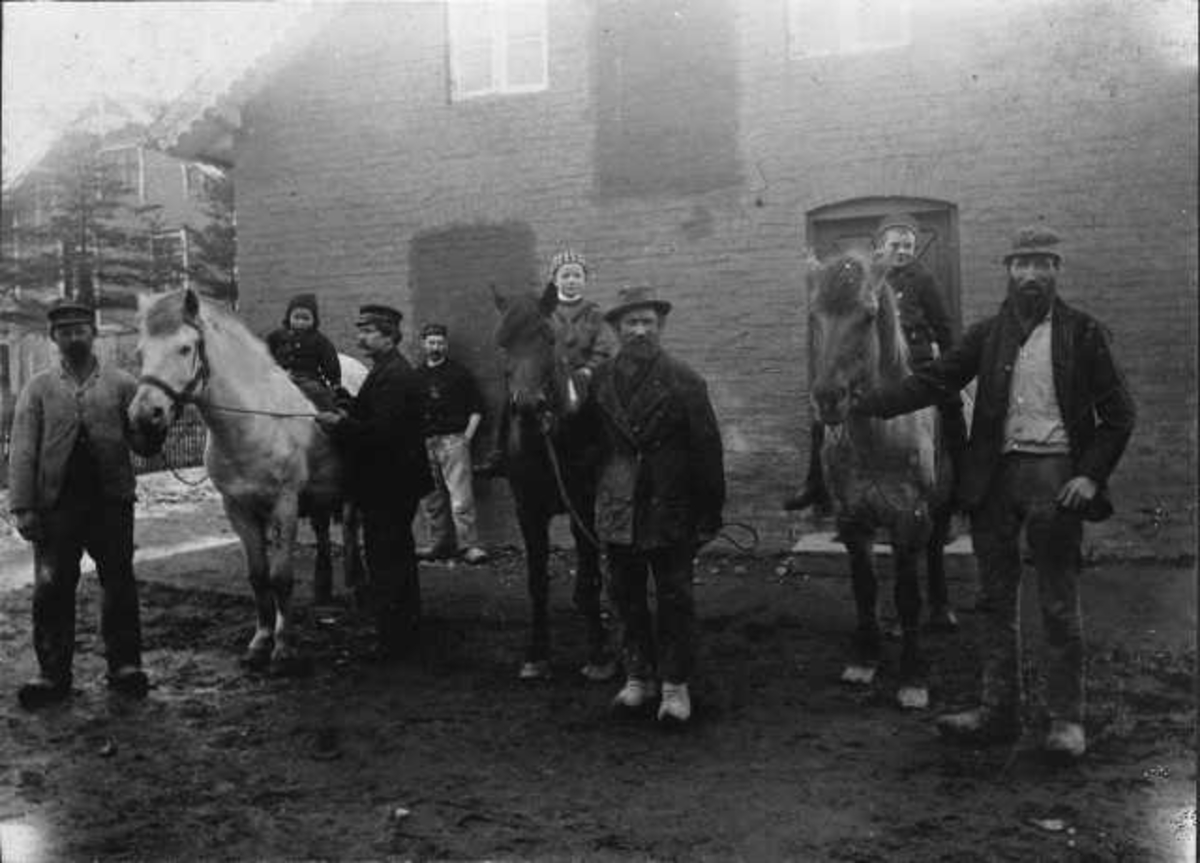 Emanuel Simonsen med hester på Hana (Hanas potteri): de tre menn som holder hestene er f.v. Herjus Stenersen, Per Østraat og Oliver Oliversen; ved veggen står Severin Christiansen, foran Emanuel Simonsen; barna på hestene er f.v. Einar Magnus Simonsen, Karl Anda og Simon Kornelius Simonsen; hestene het Kviden, Brunkå og Grollå.