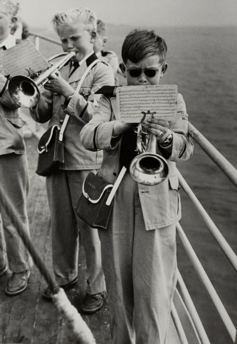 Sannsynligvis sommerturen til Jonas Øglænd Sandnes 1956 til Tau: korpsgutter spiller trompet ombord av en båt
