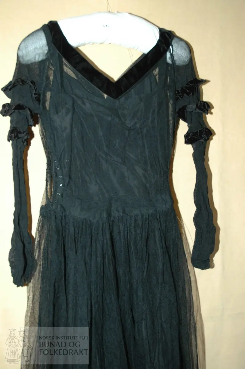 Grand galla kjole fra 1900, samt underkjole og bolero. 

Materiale: "Silketaft", truleg kunststoff, svart tyll, fløyelsband- Trykknappar i sidene. 