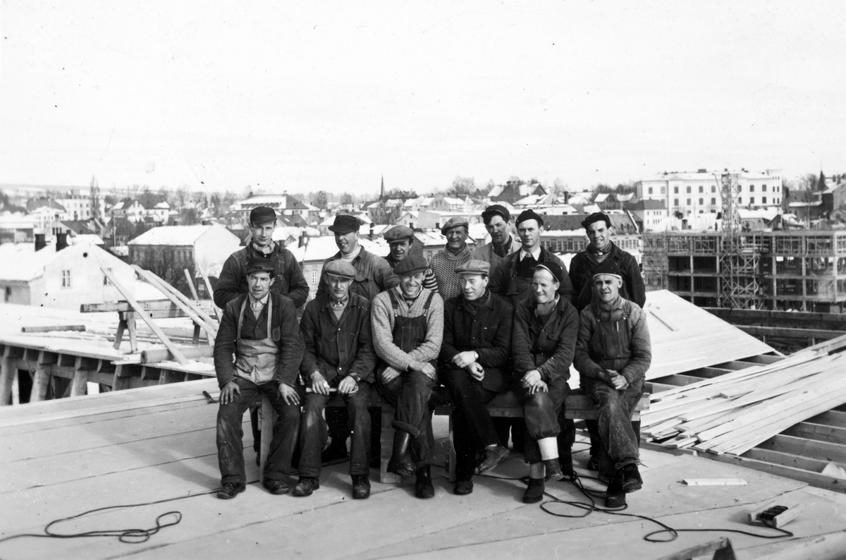 Bygningsarbeidere fra firmaet til brødrene Syverinsen, Hamar. På taket av boligblokk i Skappelsgate/Heidemannsgate, Hamar, ca 1953-1955. 
 rekke f. v. Henrik Nyhus, Vang, ukjent, ukjent, ukjent, Sverre Tangen, Hamar, ukjent. 2. rekke f. v. ukjent, ... Nyhus, ukjent ukjent, ukjent, Torbjørn Ingvaldsen, Kristian Tangen. 