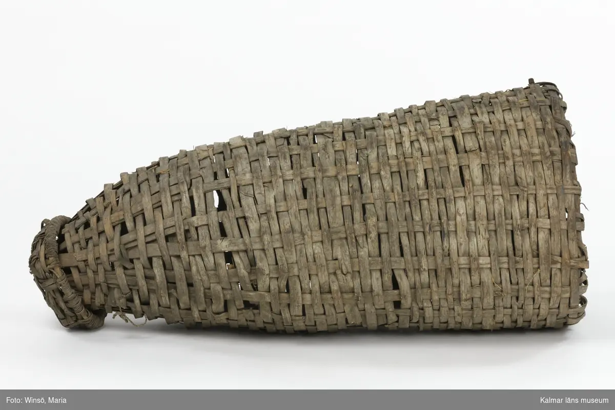 KLM 25488. Mjärde. Av flätade vidjor med vidbundet lock. Spolformad med runt tvärsnitt. En öppning i vardera ände. Vid den största öppningen en strutformad inredning. Två fastbundna snören på ena sidan.