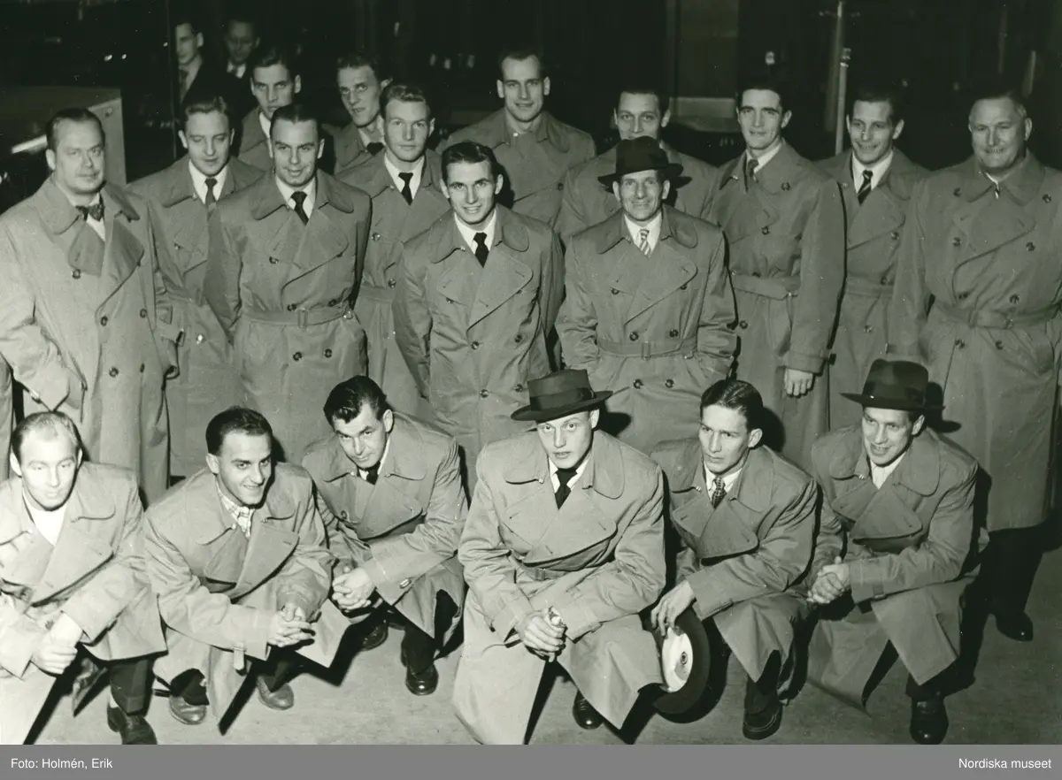 Grupporträtt av män i rockar. Troligtvis svenska herrlandslaget i fotboll, tidigt 1950-tal. Putte Kock längst till vänster i mittersta raden, samt Kalle Svensson sittandes i mitten.